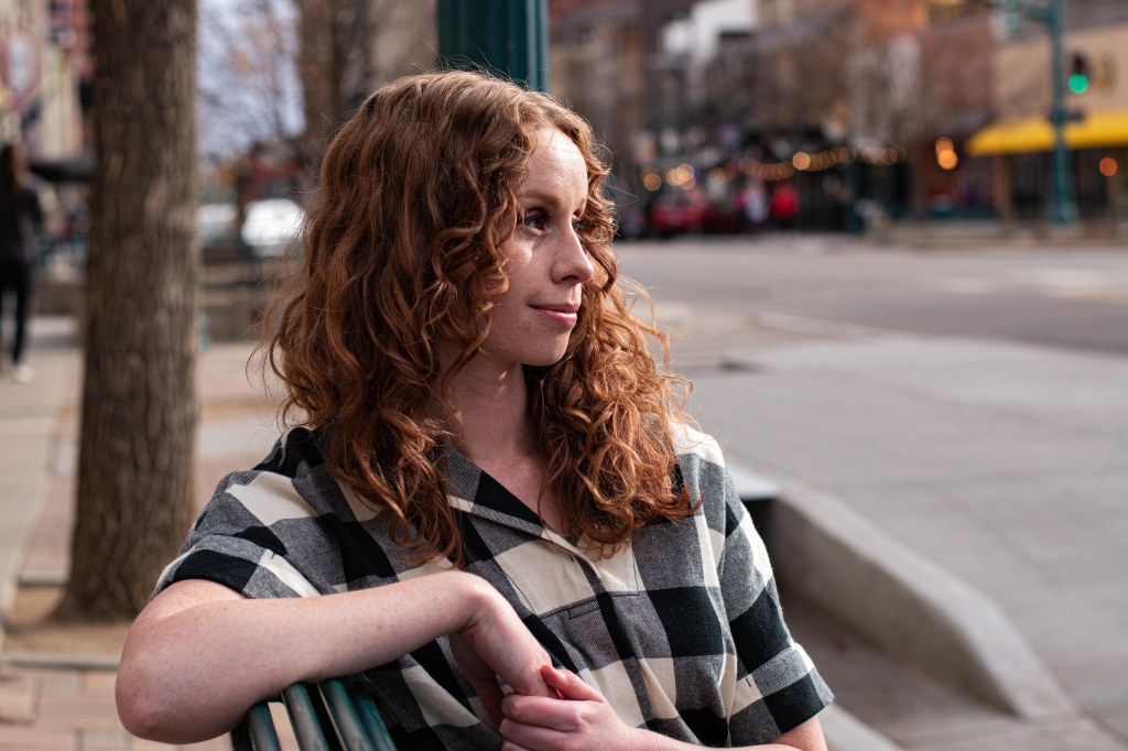 Copywriter sitting on a bench staring off camera.