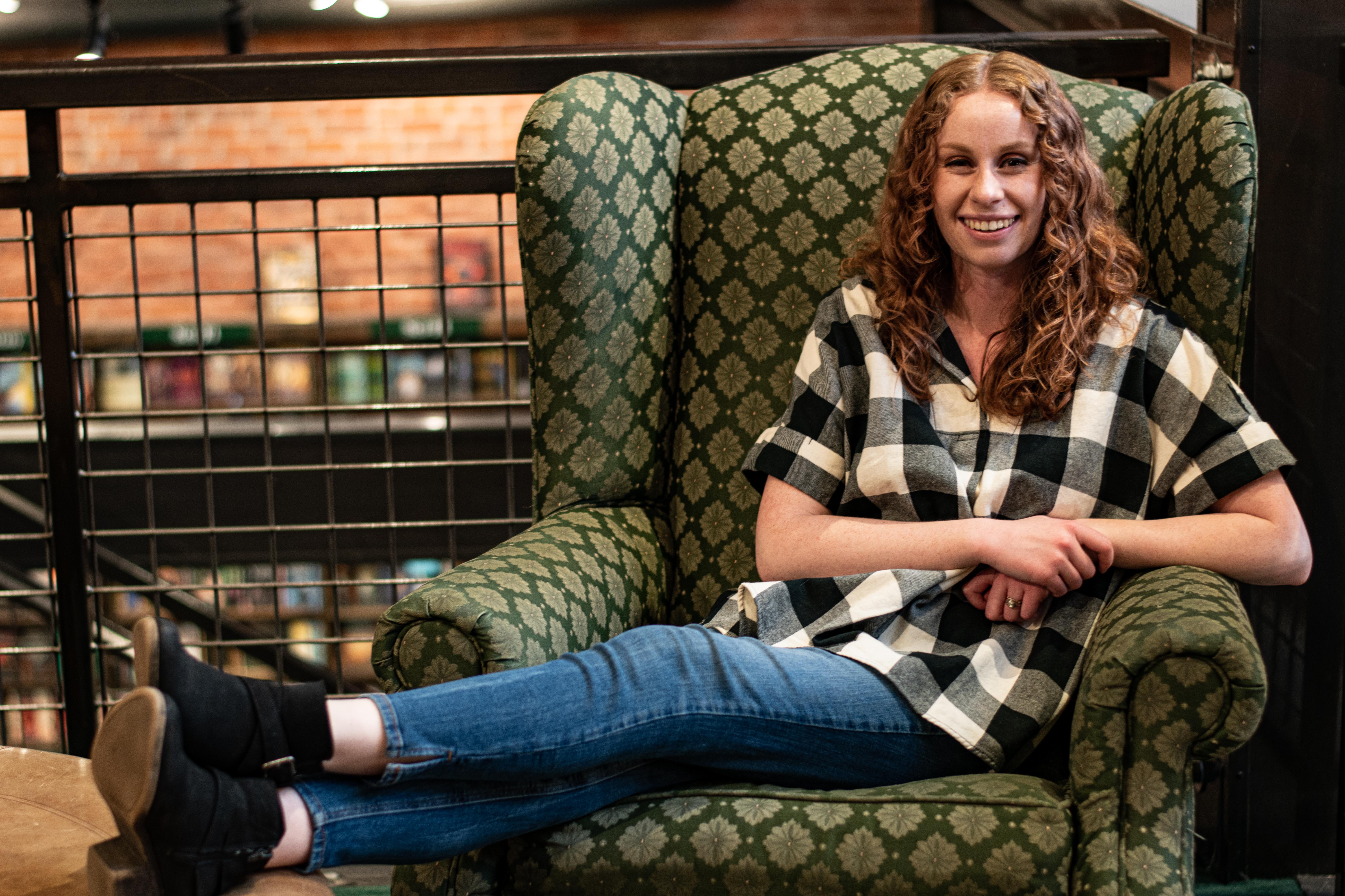 Content marketing writer sits in green upholstered arm chair.